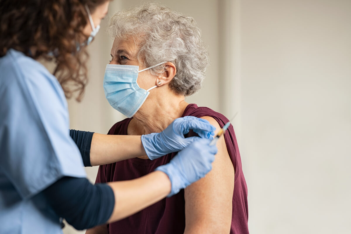 nurse giving older woman a covid vaccination