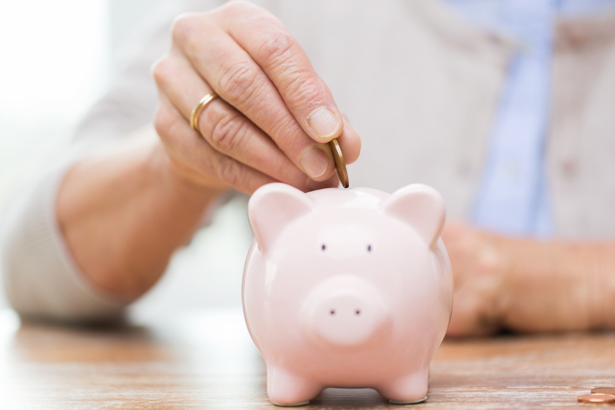 Senior Putting Coin into Piggy Bank_Franklin Park® Senior Living