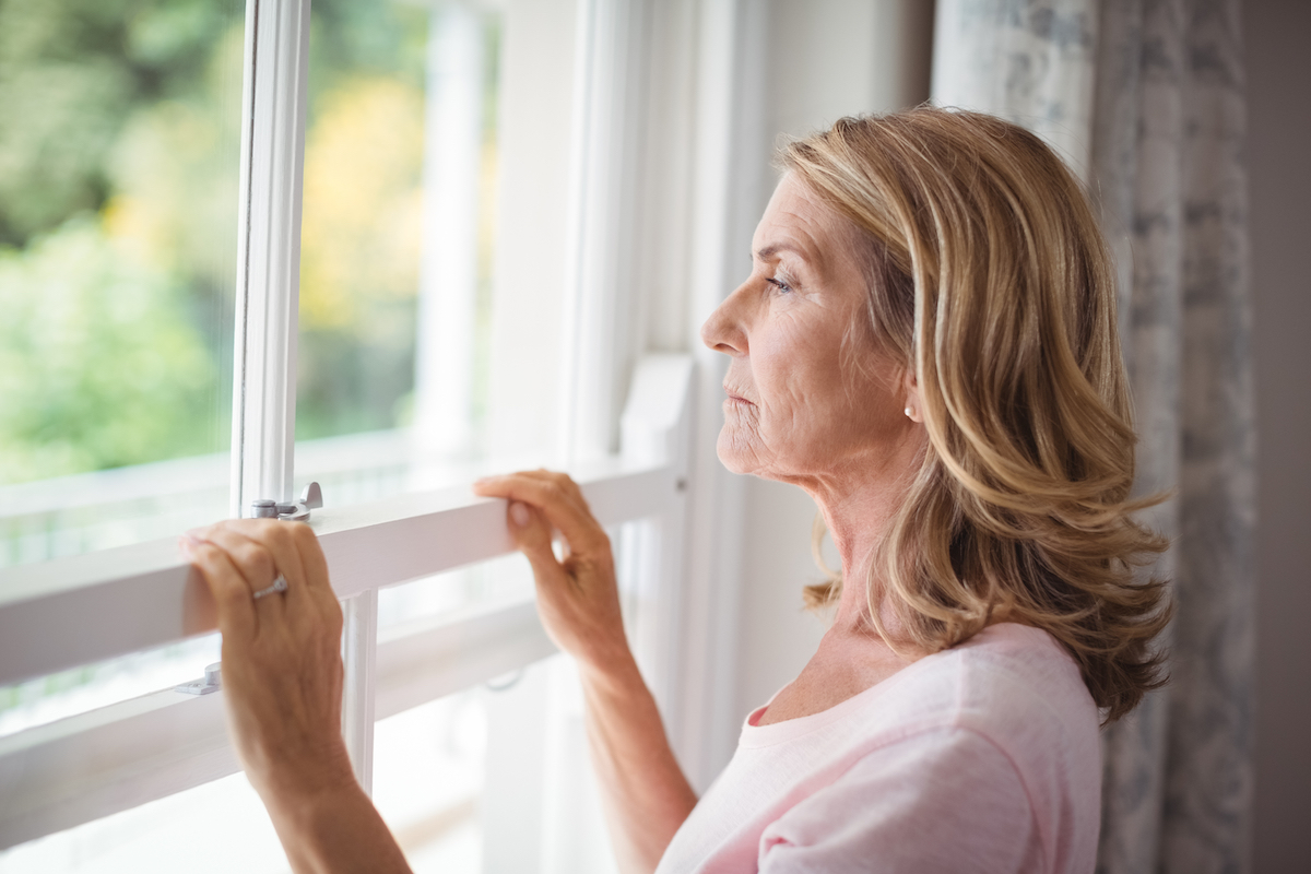 Thoughtful,Senior,Woman,Looking,Out,From,The,Window,At,Home
