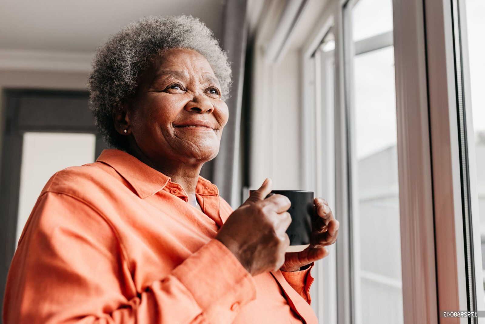 Senior woman holding mug, gazing out window
