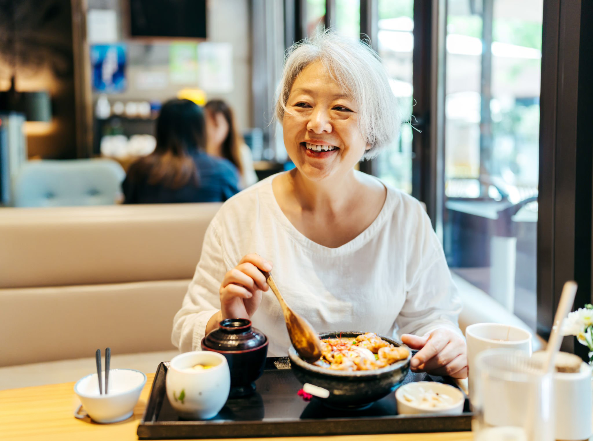 Smiling older woman eating meal in restaurant
