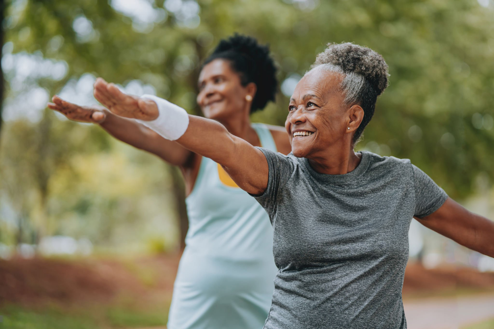 Two senior women exercising outdoors in park