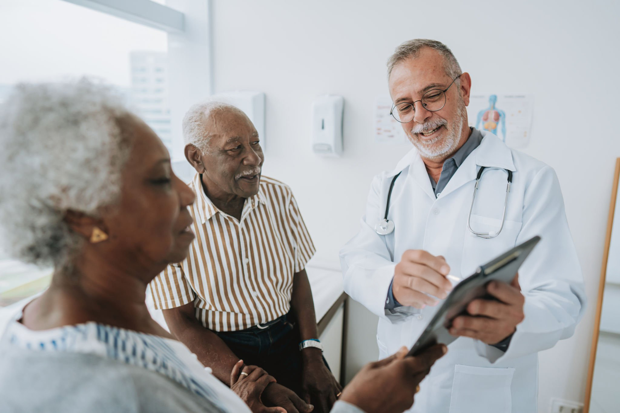 Doctor showing tablet to elderly couple