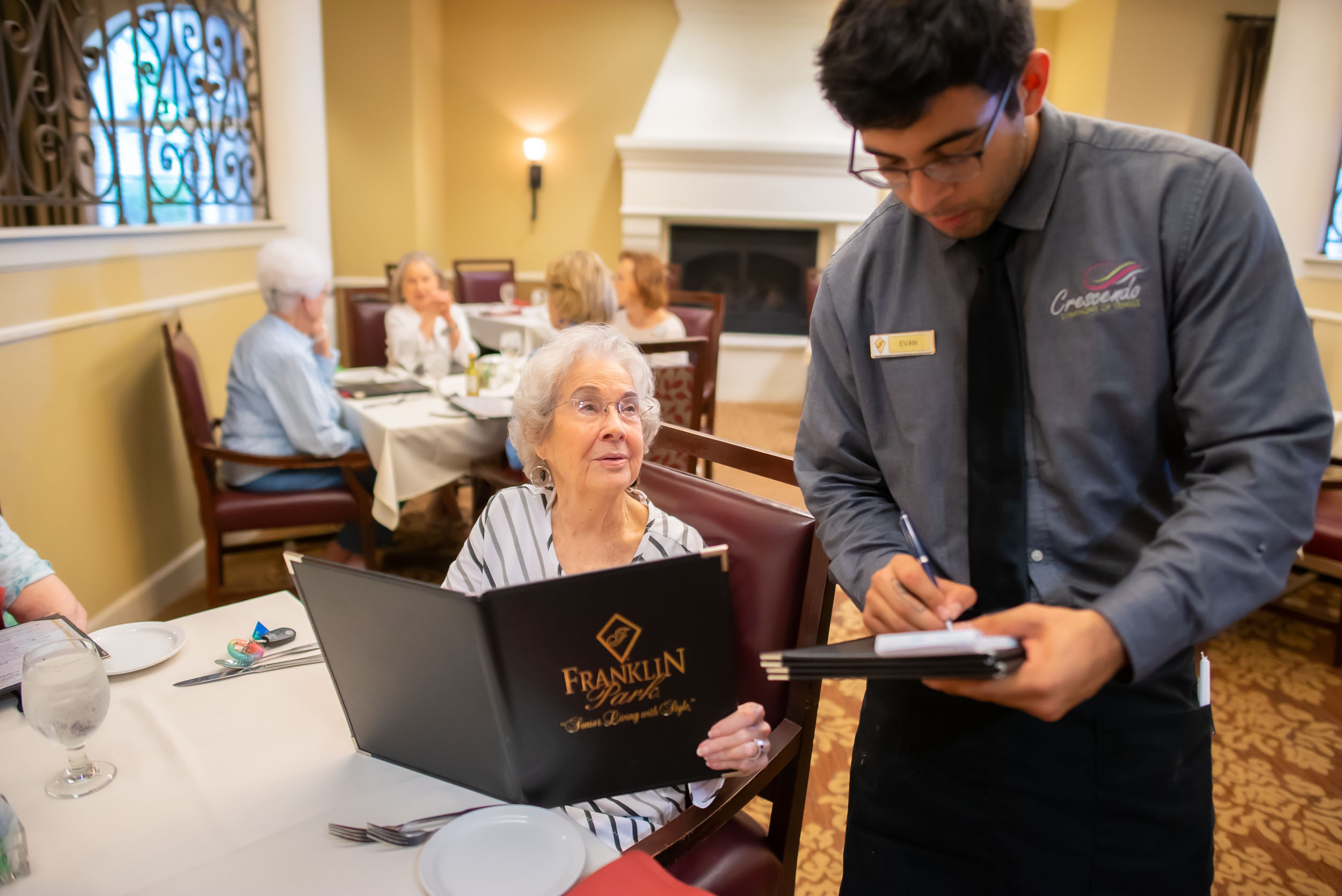 Server taking order from elderly woman in dining room