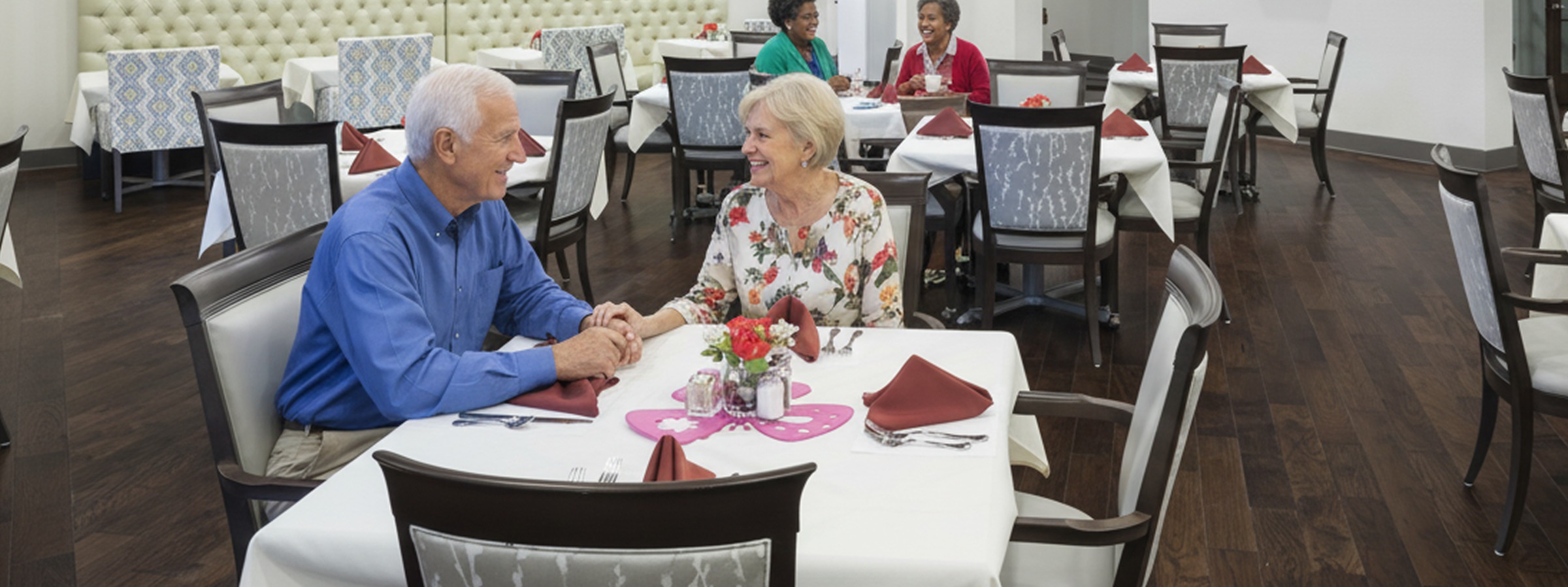Senior couple holding hands at restaurant table