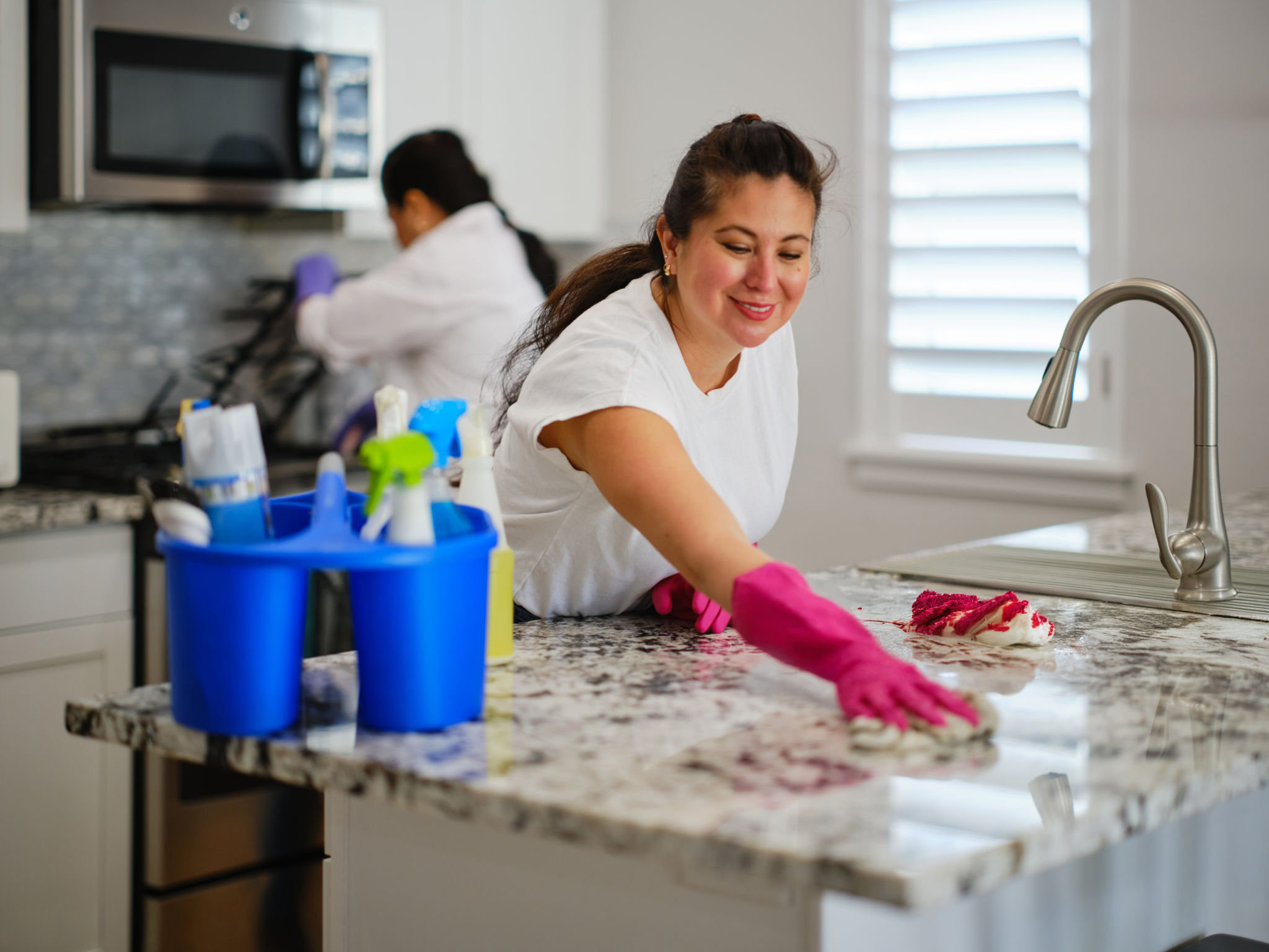 Woman cleaning kitchen countertop with pink gloves