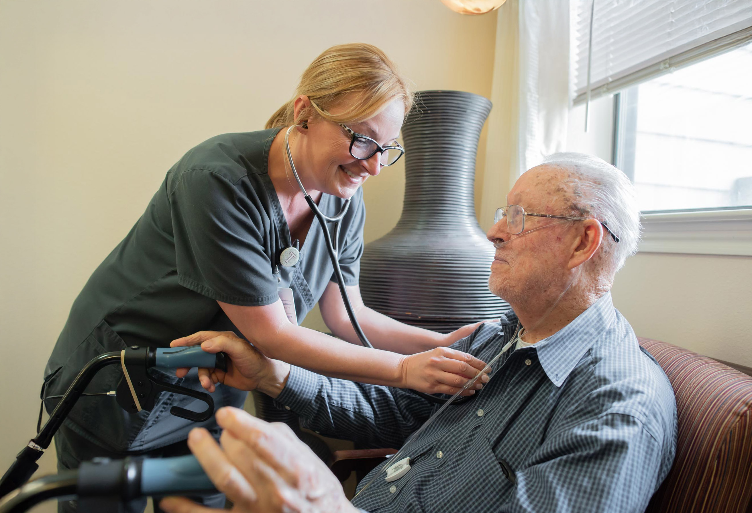 Nurse checking elderly man’s chest with stethoscope