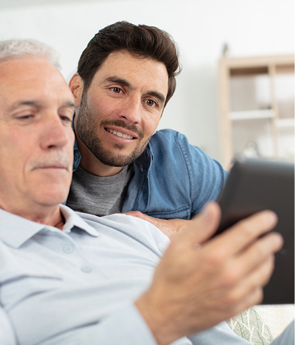 Younger man helping older man with tablet