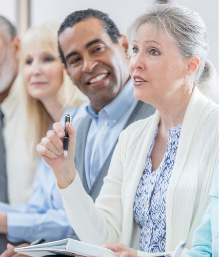 Woman speaking in meeting holding pen and notepad