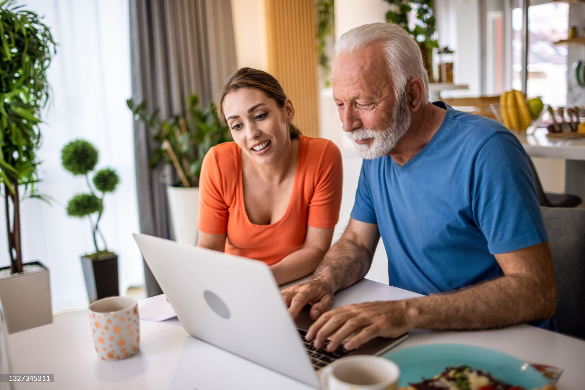 Older man and woman using laptop together at home