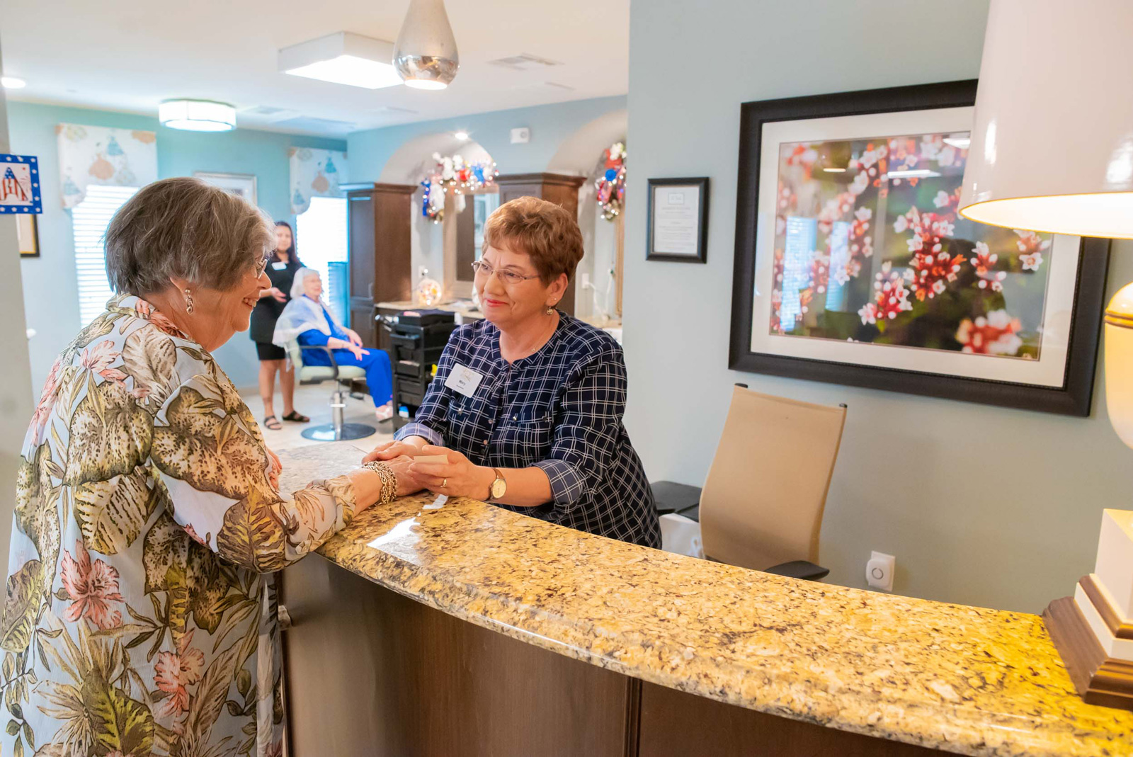 Receptionist greeting senior woman at salon front desk