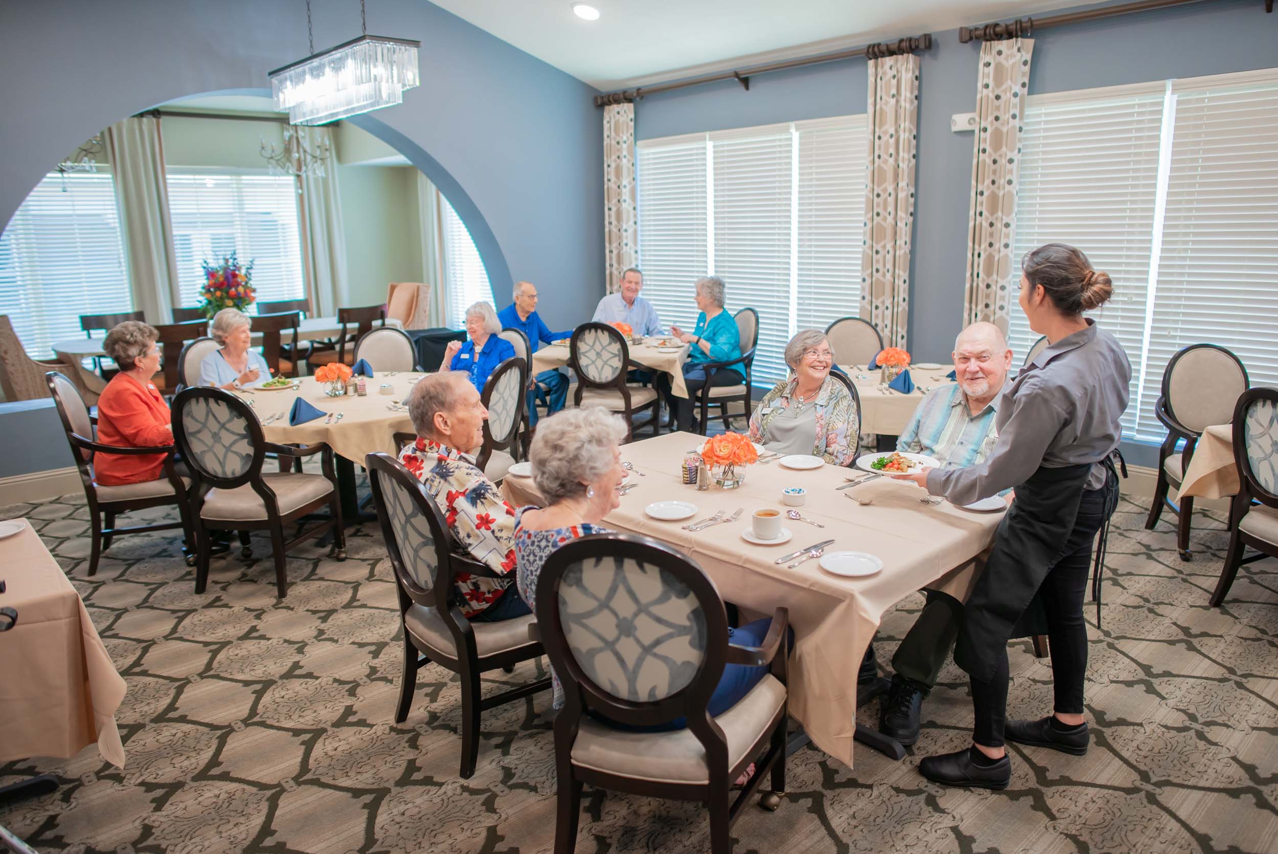 Server serving seniors in elegant dining room