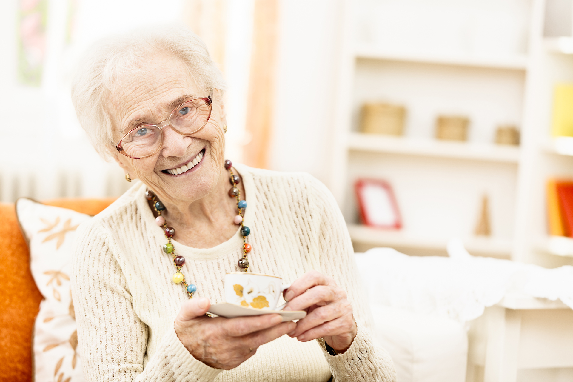 Smiling elderly woman holding teacup indoors