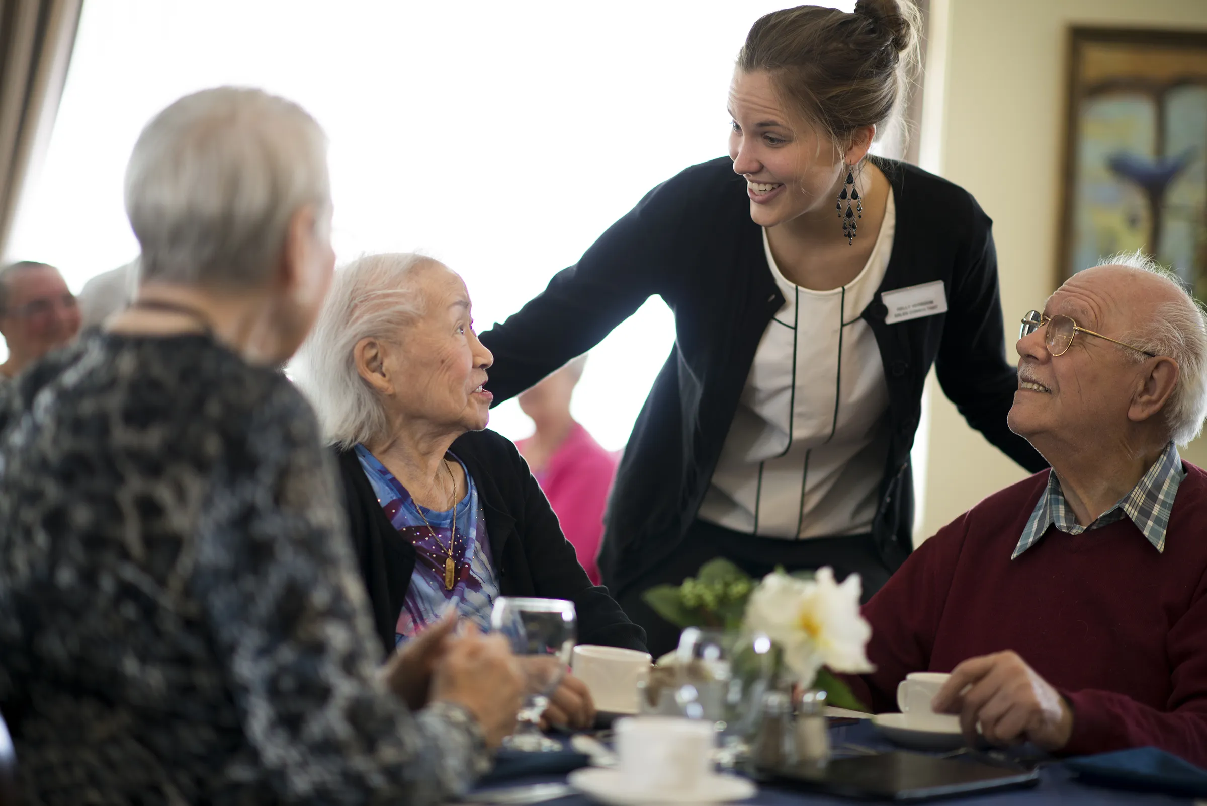 Caregiver chatting with seniors at dining table