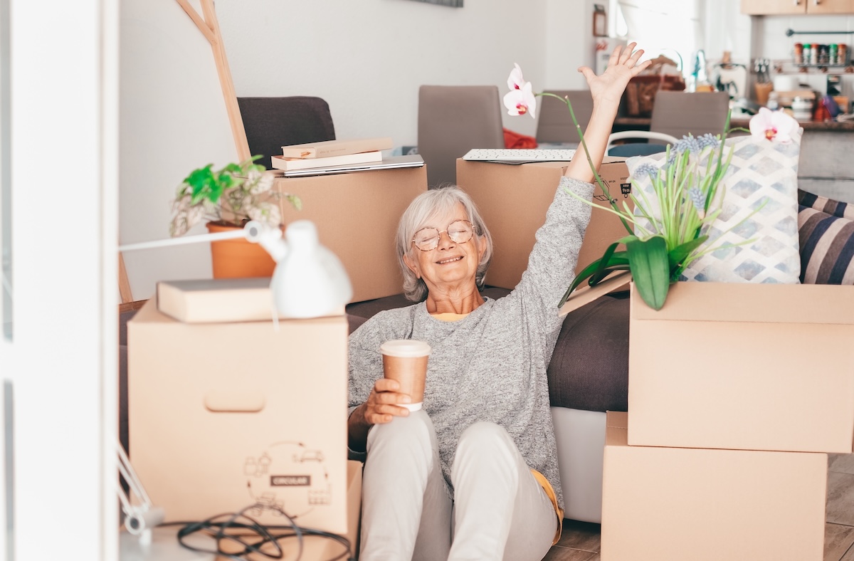 Happy,Senior,Woman,Involved,In,Moving,House,Sitting,Among,Cardboard