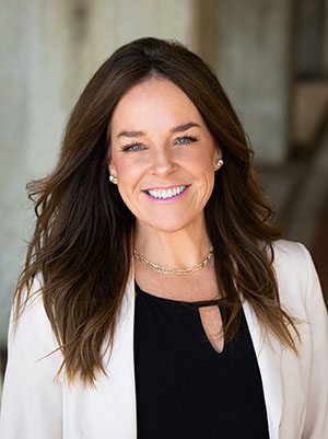 Smiling woman in blazer, professional headshot outdoors